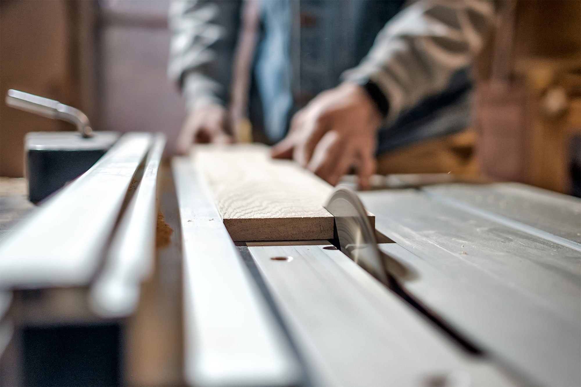 Wood board on saw table illustrating wood cabinet construction.